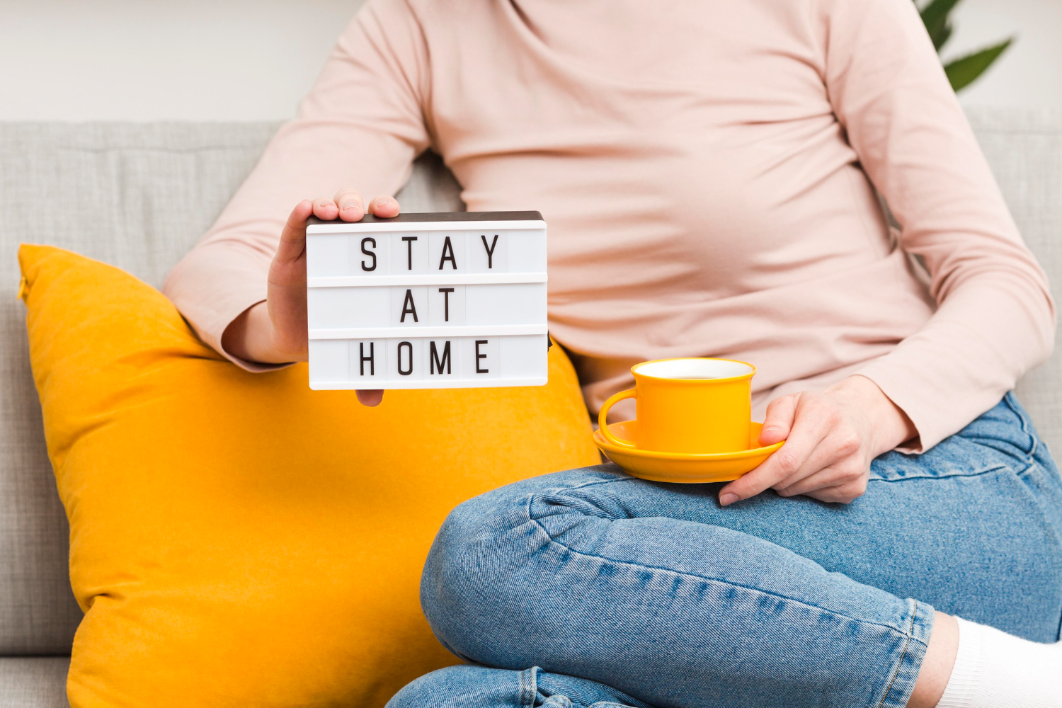 A decorative "Stay at Home" sign resting on a sofa, promoting safety and comfort during home time